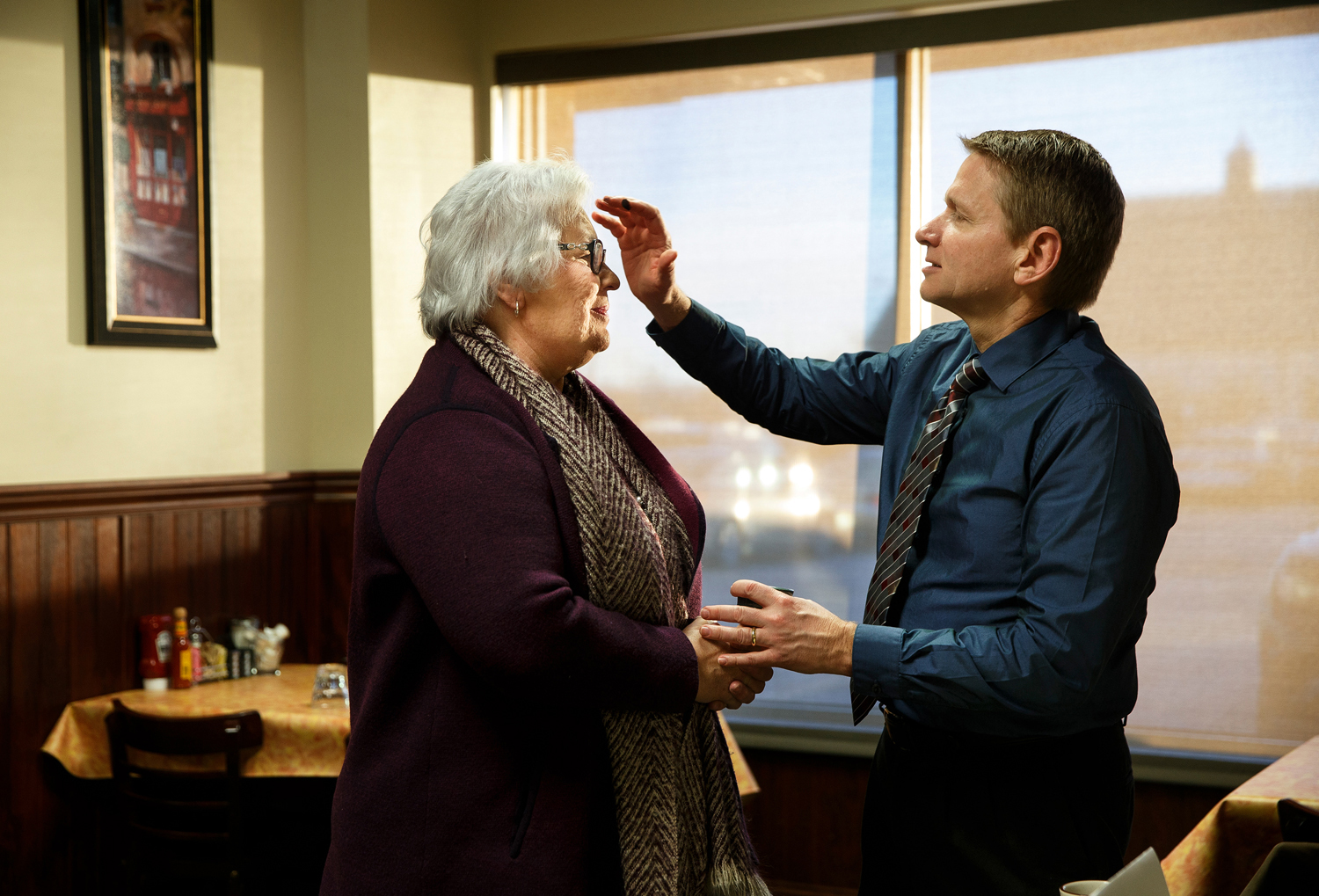 A pastor marks a parishoner with an ash cross in the middle of a restaurant during an Ash Wednesday service.