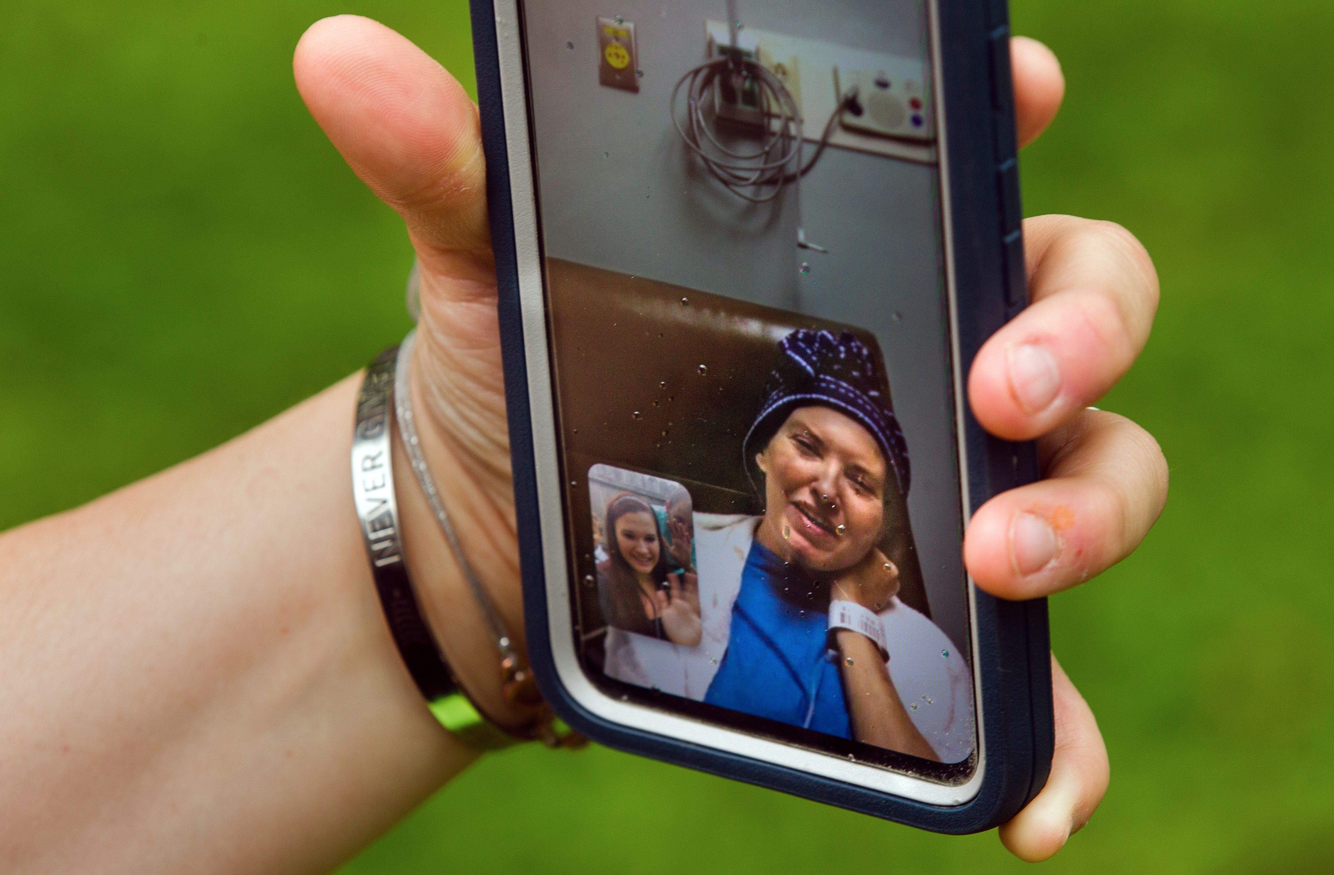Woman hospitalized with COVID-19 appears on cell phone during video call.