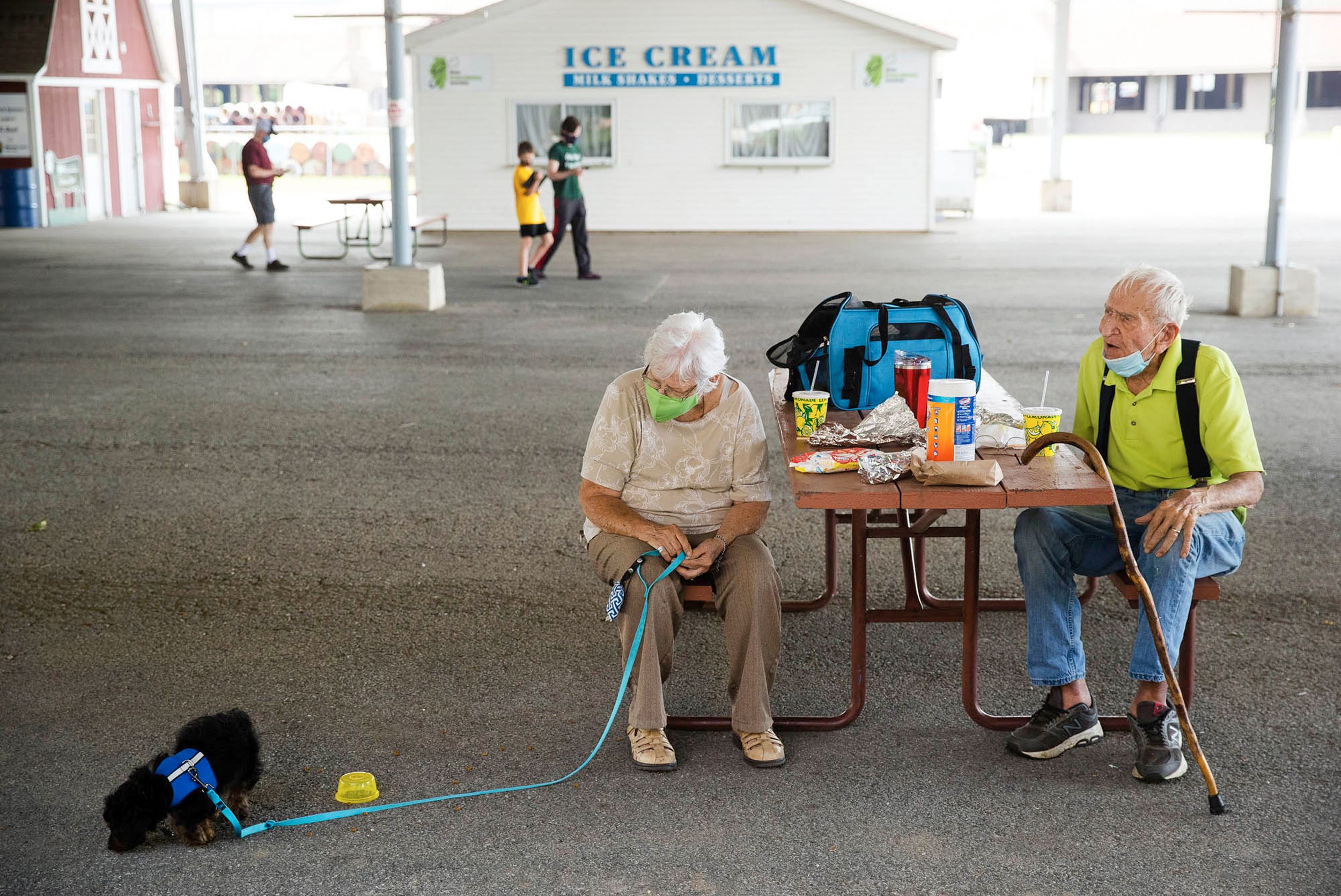 An elderly couple picnic with their dog at Illinois State Fairgrounds that is virtually empty after being cancelled for 2020 due to COVID-19.
