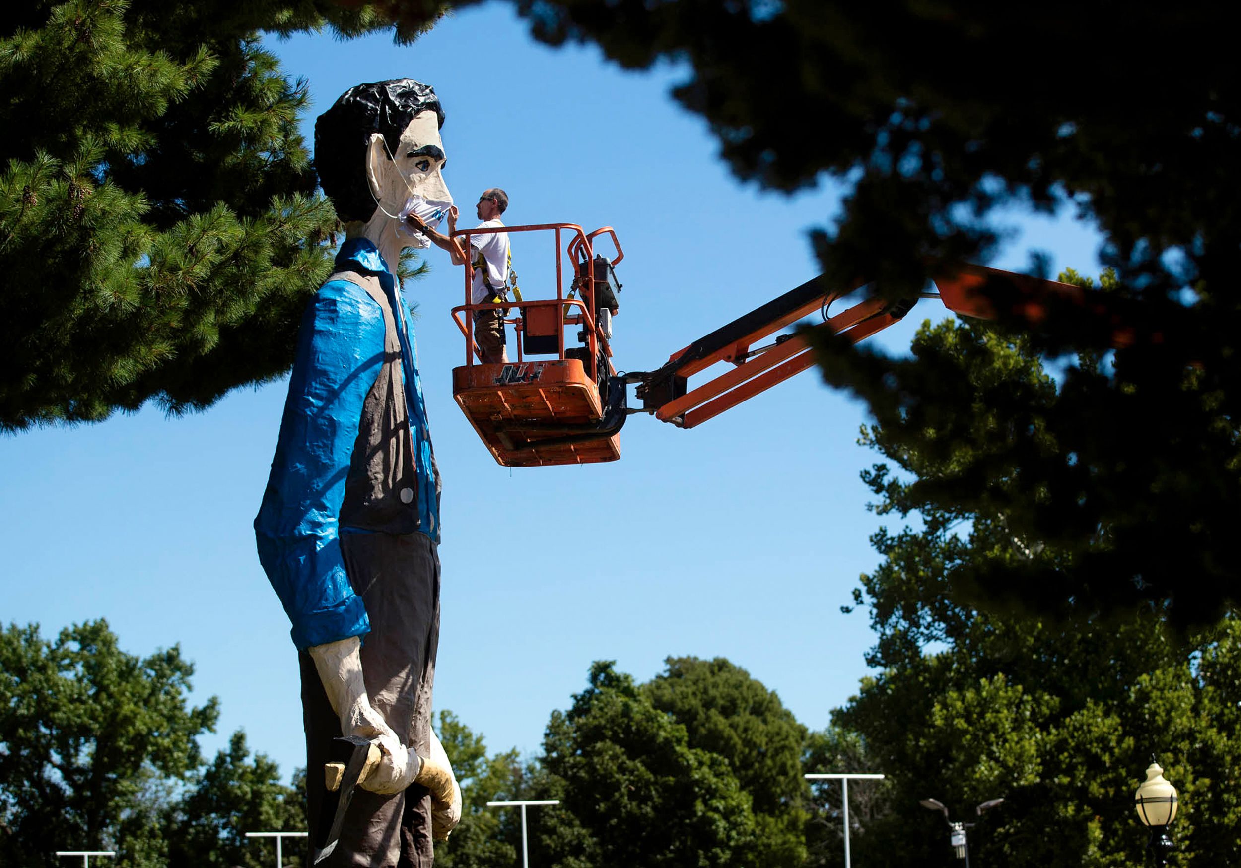 A worker in a boom lift installs a mask over the face of a giant Abe Lincoln statue on the Illinois State Fairgrounds in September 2020.