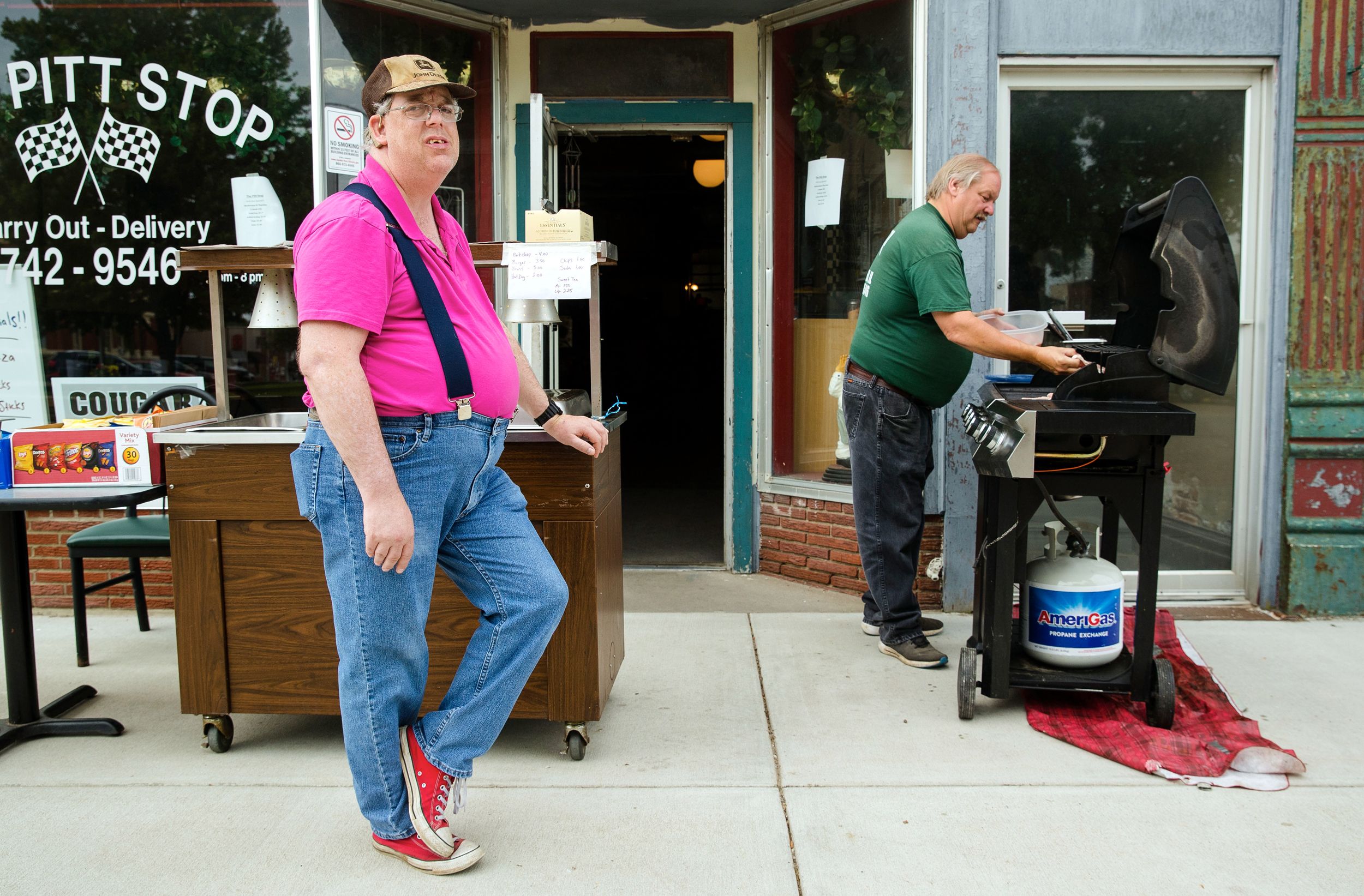 Two men stand near a grill at The Pitt Stop restaurant on Winchester, Illinois town square during COVID-19 pandemic, May 2020.