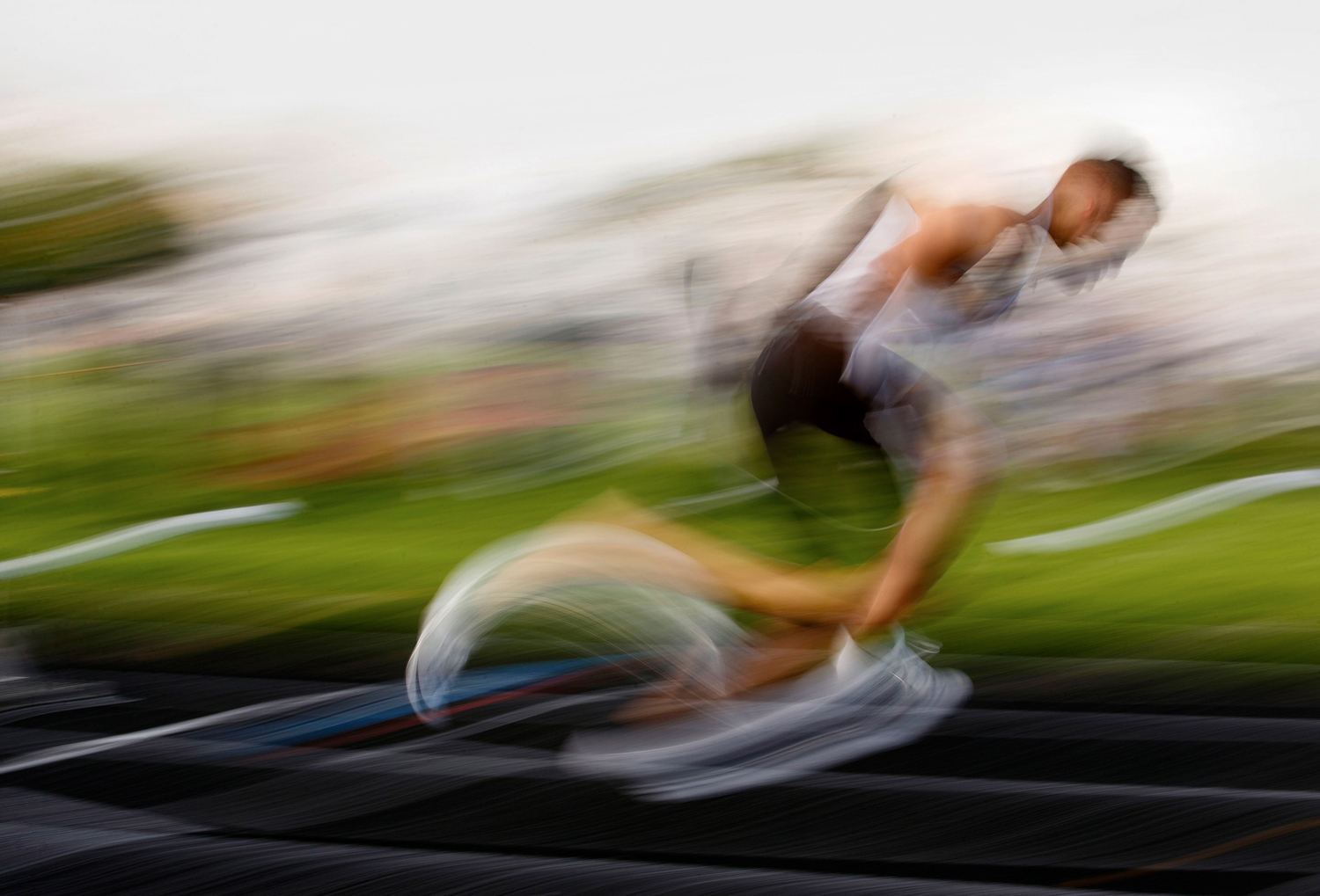 An athlete's motion is blurred during a long exposure as he runs during a track event.