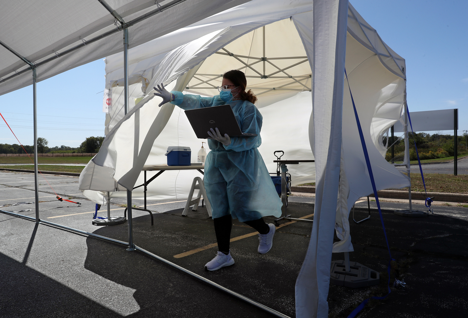 A medical worker exits a tent outfitted in full protective gear to administer a covid test in a parking lot during the Covid-19 pandemic.