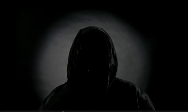 Silhouette of person wearing a hoodie; their face is in complete shadow.