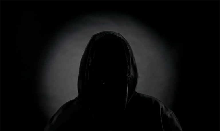 Silhouette of person wearing a hoodie; their face is in complete shadow.
