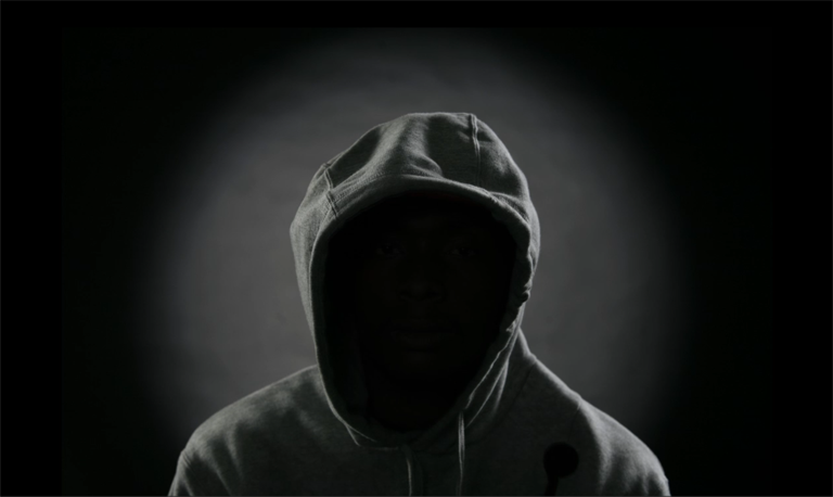 Silhouette of person wearing a hoodie; their face is in complete shadow.