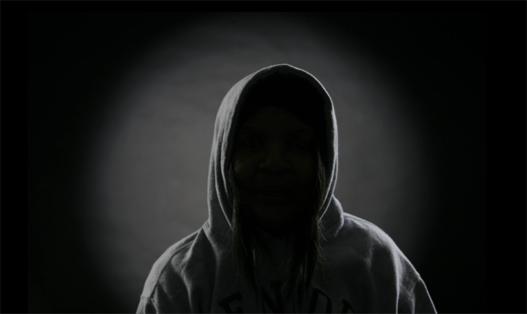 Silhouette of person wearing a hoodie; their face is in complete shadow.