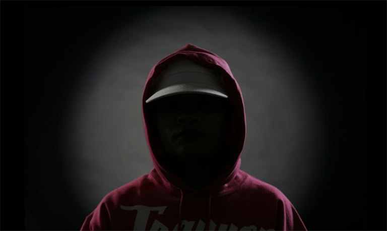 Silhouette of person wearing a hoodie; their face is in complete shadow.