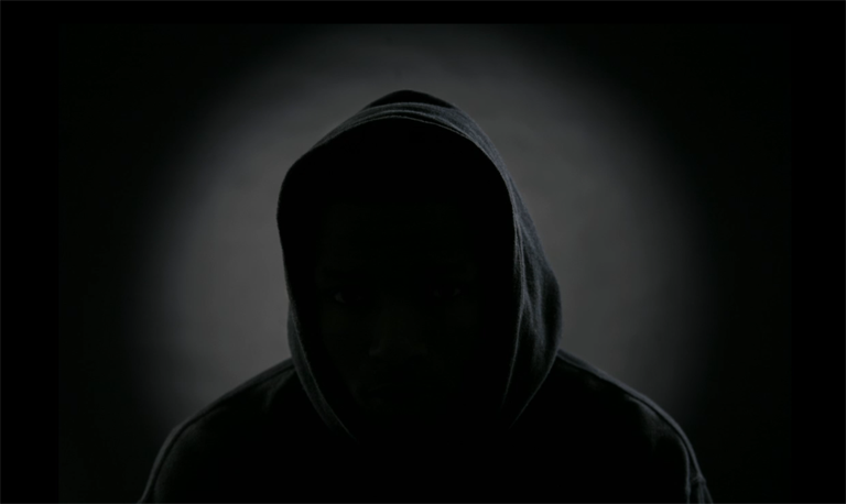 Silhouette of person wearing a hoodie; their face is in complete shadow.