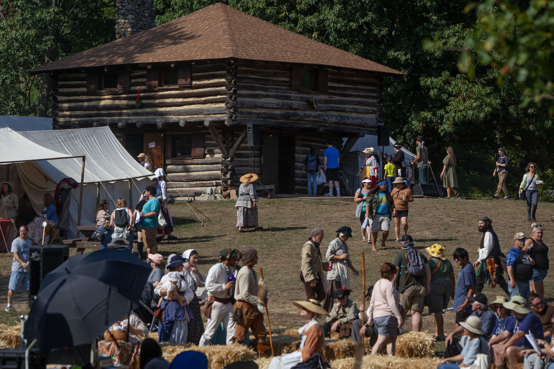 Reenactors in colorial-era dress mill about a colonial=era fort constructed of logs.