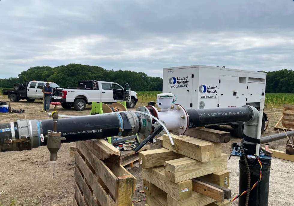 An above-ground section of plumbing from a test well is supported underneath by heavy lumber.